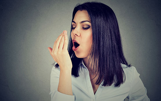 Woman checking her breath with hand.