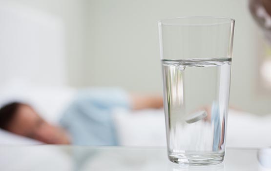 Close up of glass of water with sick man in background